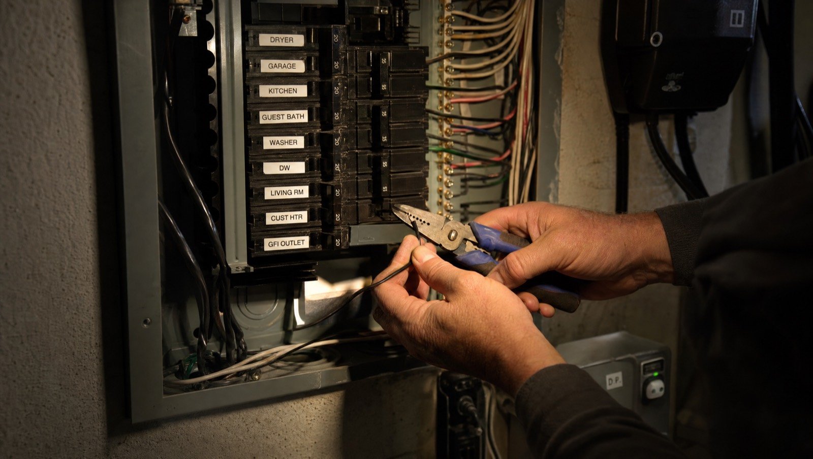 Electrician working in a labeled electrical panel by headlamp